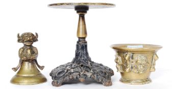 A heavy cast brass bowl with face decoration, along with a similar styled bell with figure to top,