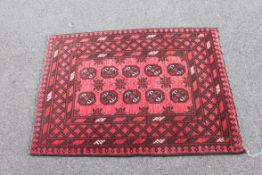 An Indian deep pile rug having red ground with elephant foot design to centre,