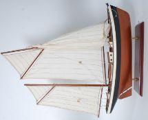 A wooden 20th century model of a sailing ship complete with canvas sails raised on plinth base.
