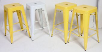 A set of 4 20th century Industrial metal stools, 3 yellow and one in white.
