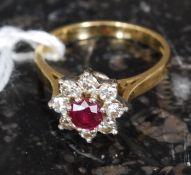 An 18ct yellow gold ruby and diamond ring. The central ruby with surrounding diamonds.