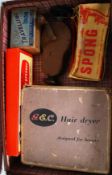 A vintage leather suitcase with retro boxed items such as a hair dryer,