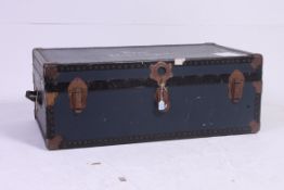 A vintage blue shipping / steamer trunk with metal handles and banding with notation to top.