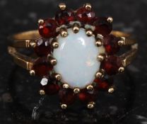 A ladies 9ct gold opal ring with ruby garnet stone surround set on plain shank.