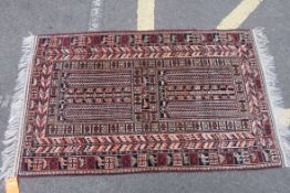 A Persian style wool rug having red ground being decorated with trees,
