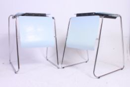A pair of metamorphic office chairs than convert to desks raised on chrome supports with resin set