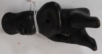 A South American black clay  whistle being carved as a seated man with hole to rear and centre