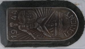 A Second World War Third Reich Nazi Lorient Battle arm shield (silver) set on green cloth back.