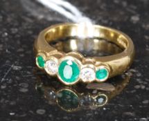 An 18ct gold diamond and emerald ring, the three emeralds with diamonds interspersed.