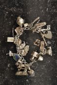 A silver charm bracelet having many charms adorned to include iron, snail, carriage, horseshoe,