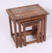 A Jacobean style carved oak nest of tables being raised on squared legs with stretchers having