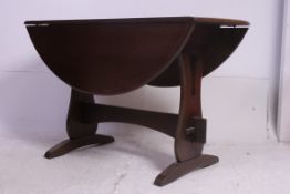 A 20th century Ercol style oak drop leaf dining table raised on lyre shaped supports with central