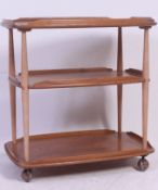 A 1970's Ercol blonde oak three tier tea trolley with galleried tiers raised on castors,