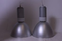 A pair of large oversized contemporary Industrial lights with large polished metal shades and