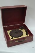 A cased vintage 1940's 1950's portable record player in claret containing a Gerrard record deck,