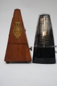 Two vintage metronomes one being of wooden construction and the other being bakelite.