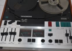 A vintage Reel to Reel Tandburg recorder tape player, having a teak housing and a smoked lid

UK,