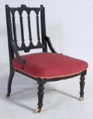 An Victorian ebonised nursing chair on turned legs with white ceramic castors having overstuffed