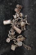 A silver charm bracelet habing many charms include carriage, cart, tankard, chair, animals, etc.