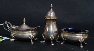 A silver hallmarked mustard pot raised on pad feet with a blue glass liner with a hallmarked pepper