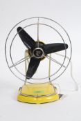 A vintage 1970's yellow retro Pifo table top desk fan with caged black fans.