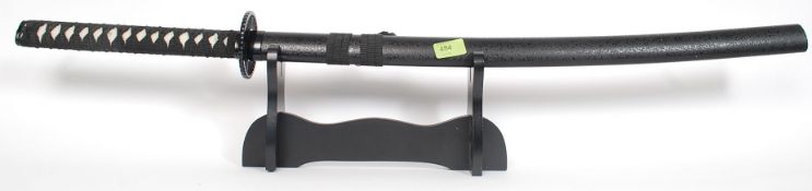 A replica ' Kill Bill ' sword being complete with scabbard and fabric handle. Set on display stand.