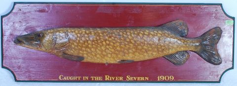 A large wooden faux taxidermy pike mounted onto an oversized wooden painted board with resin set