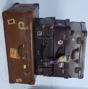 A stack of vintage 20th century suitcases to include a large leather example with applied vintage