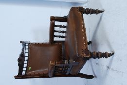 A Victorian mahogany library armchair raised on turned legs with faux brown leather seat and back