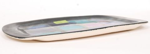 An Eric Leaper studio pottery dish being decorated with green, purple and pink design,