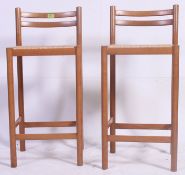 A pair of beech wood and rattan upholstered bar stools having low back rests with peripheral