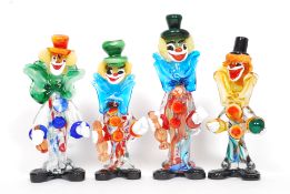 A group of 4 Murano coloured / studio glass clowns all holding small studio glass items.