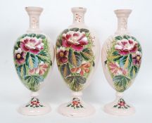 A set of three Victorian glass painted vases, each decorated with floral panels,