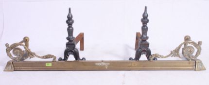 A vintage brass fire fender along with a pair of cast iron fire dogs.