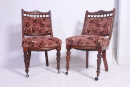A pair of Victorian mahogany dining chairs raised on turned vase legs with overstuffed seats and