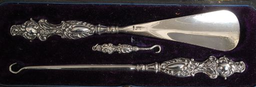 A cased silver hallmarked set of button hooks and shoe horn.