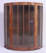 A 1930's Art Deco walnut bow front display cabinet having glass shelves with central door.