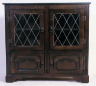 A Jacobean style oak and leaded glass display cabinet raised on bracket feet with twin doors having