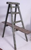 A vintage 20th century painted industrial wooden folding large trestle complete with plank having