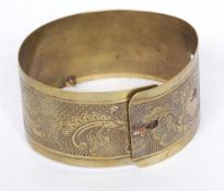 A decorative wide brass dog collar having rococo scrollwork and plain cartouche.