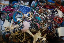 A large box of assorted vintage and contemporary costume jewellery to include brooches, bangles,