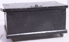 A vintage ebonised pine tool box / trunk having a hinged top being raised on later castors.