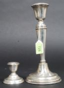 A silver hallmarked candlestick together with a smaller silver hallmarked candlestick.