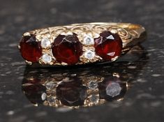 A hallmarked 9ct gold ring set with 3 garnets and 4 2pt diamonds in a scrolled mount. Size Q.