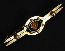 A 9ct twin bar brooch with central floral motif and applied finials. Marked 9ct. Weight 1.