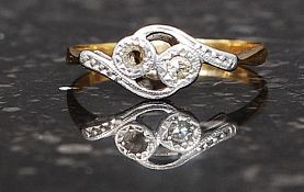 An 18ct gold and diamond ring having swirl mount inset 2pnt diamond with one diamond missing,