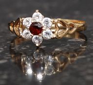 A 9ct gold hallmarked cluster ring set with CZ and central garnet within heart shaped shoulders.