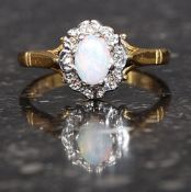 An 18ct gold cluster ring set with central opal stone surrounded by 8 1pt diamonds.