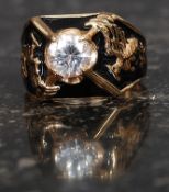 A gilded silver 925 fraternity ring with central large clear stone flanked by griffins either side.