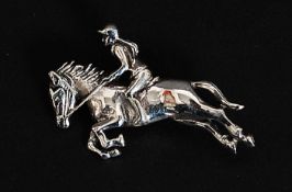 A contemporary decorative silver brooch in the form of a horse and jockey - horse racing interest.